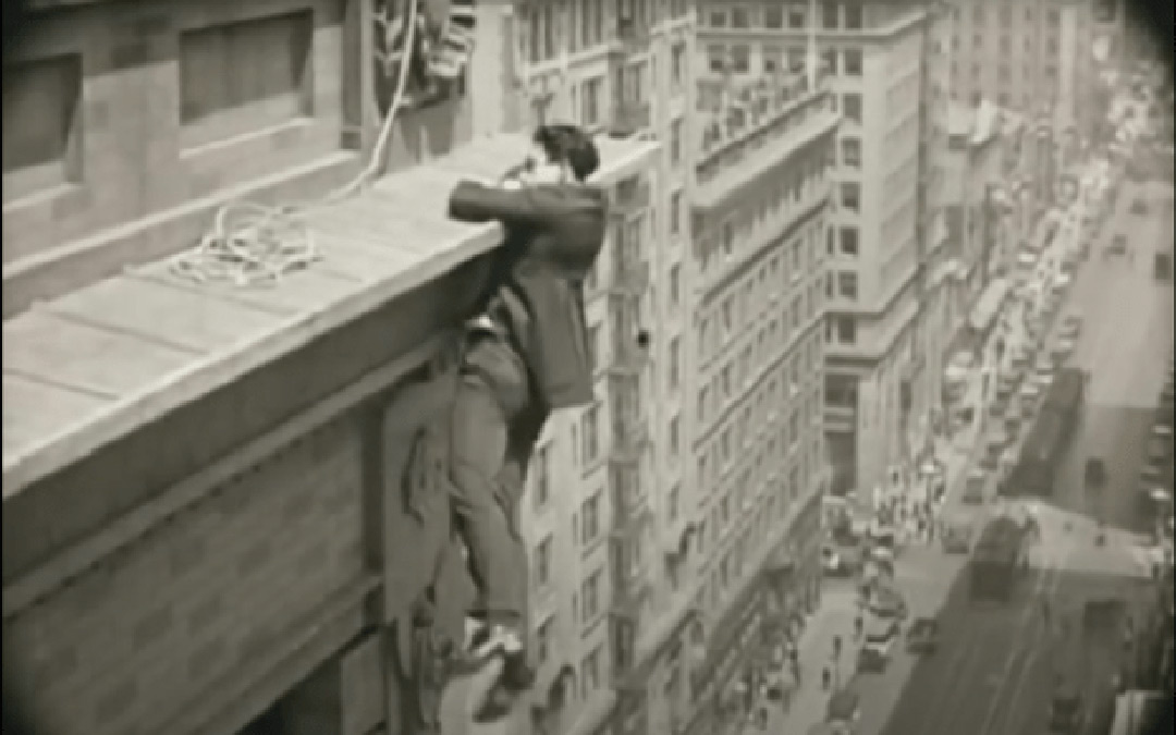 Harold Lloyd hanging from top of building